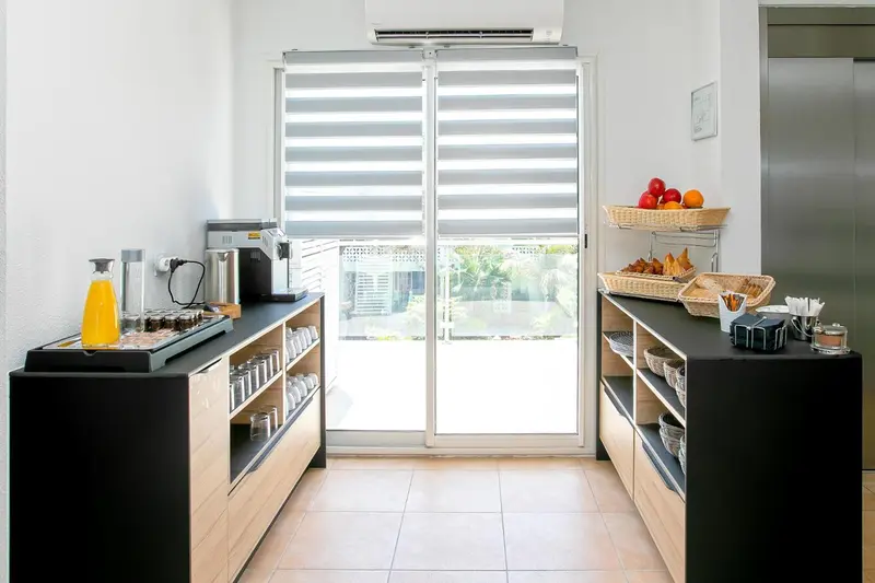 Un comptoir de petit-déjeuner avec des boissons et des pâtisseries près d'une baie vitrée.