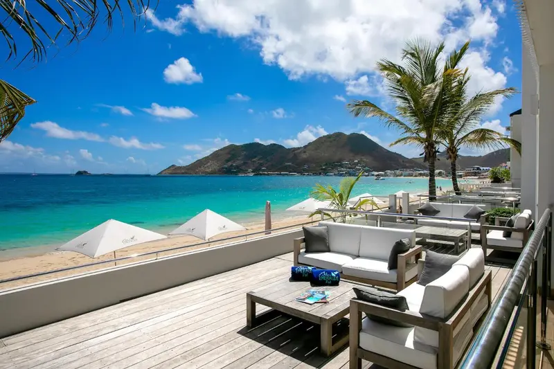 Terrasse aménagée avec des canapés et des tables basses face à la mer.