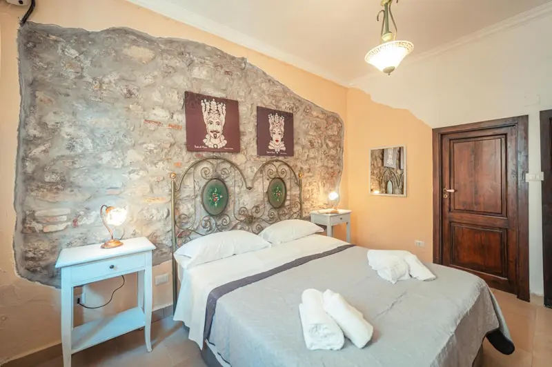 Une chambre à coucher avec un lit double et un mur en pierre.