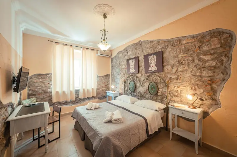 Une chambre lumineuse avec un lit double et un mur en pierre.