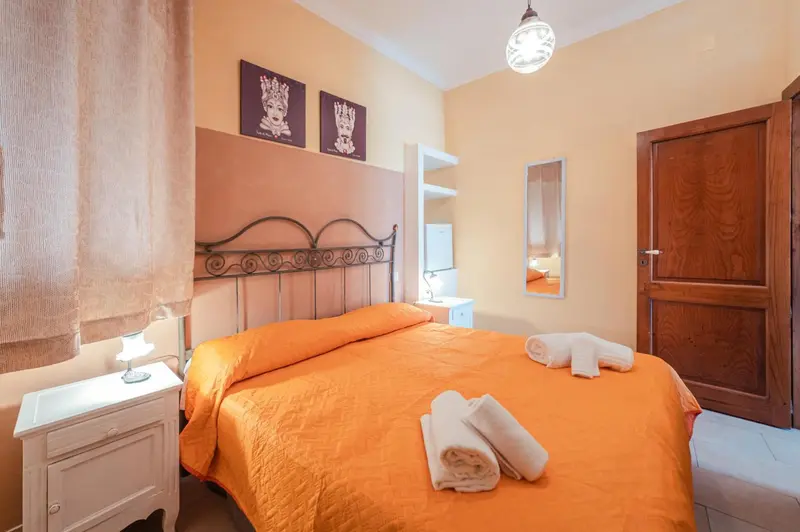 Une chambre à coucher lumineuse avec un lit recouvert d'une courtepointe orange.