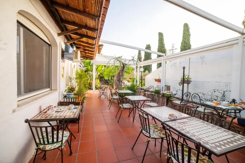 Terrasse ombragée avec tables et chaises pour le petit-déjeuner.