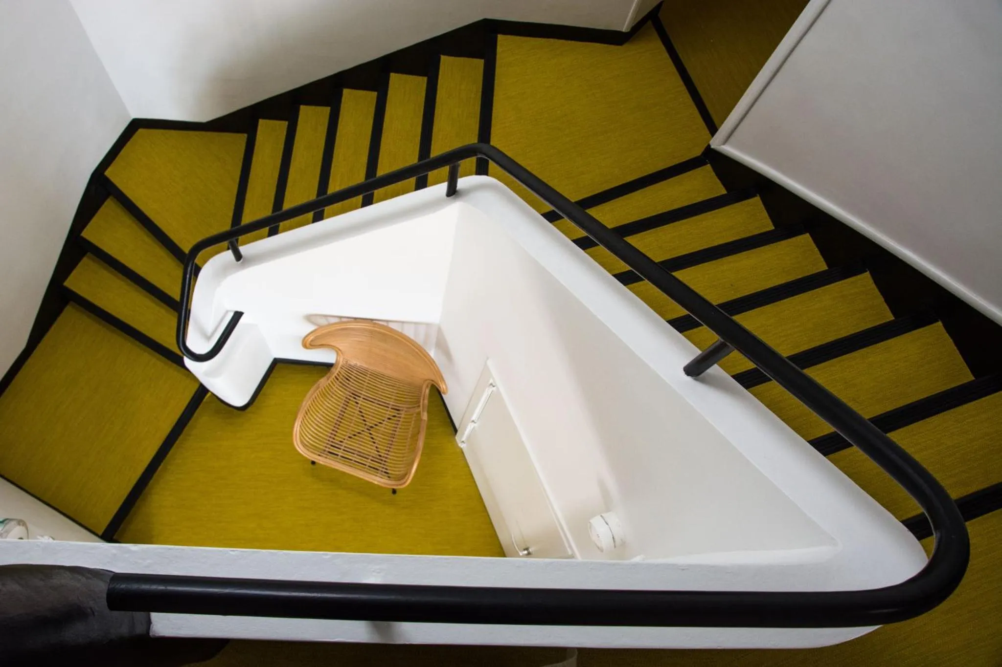 Escalier en colimaçon avec une chaise en rotin au repos.