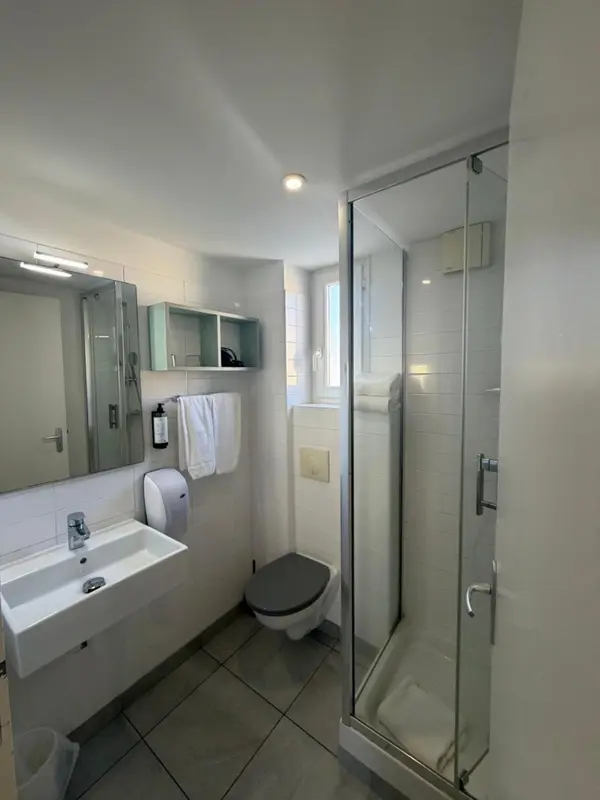Une salle de bain claire avec douche à l'italienne et lavabo.