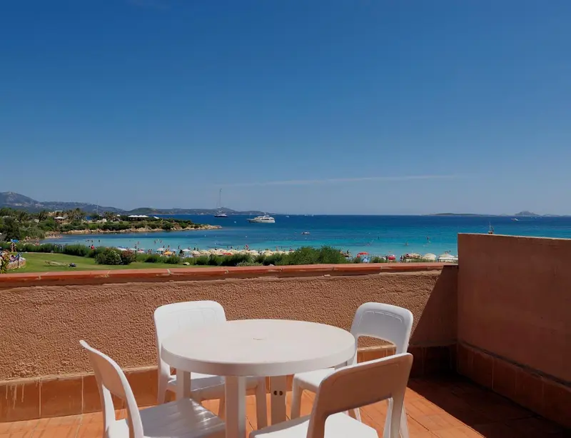 Terrasse avec table et chaises donnant sur une plage et la mer.