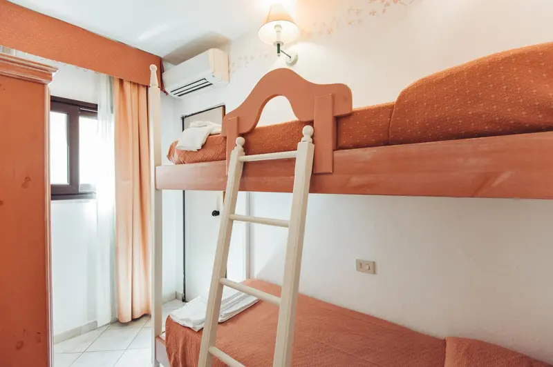Une chambre avec un lit superposé en bois clair et des murs orange.