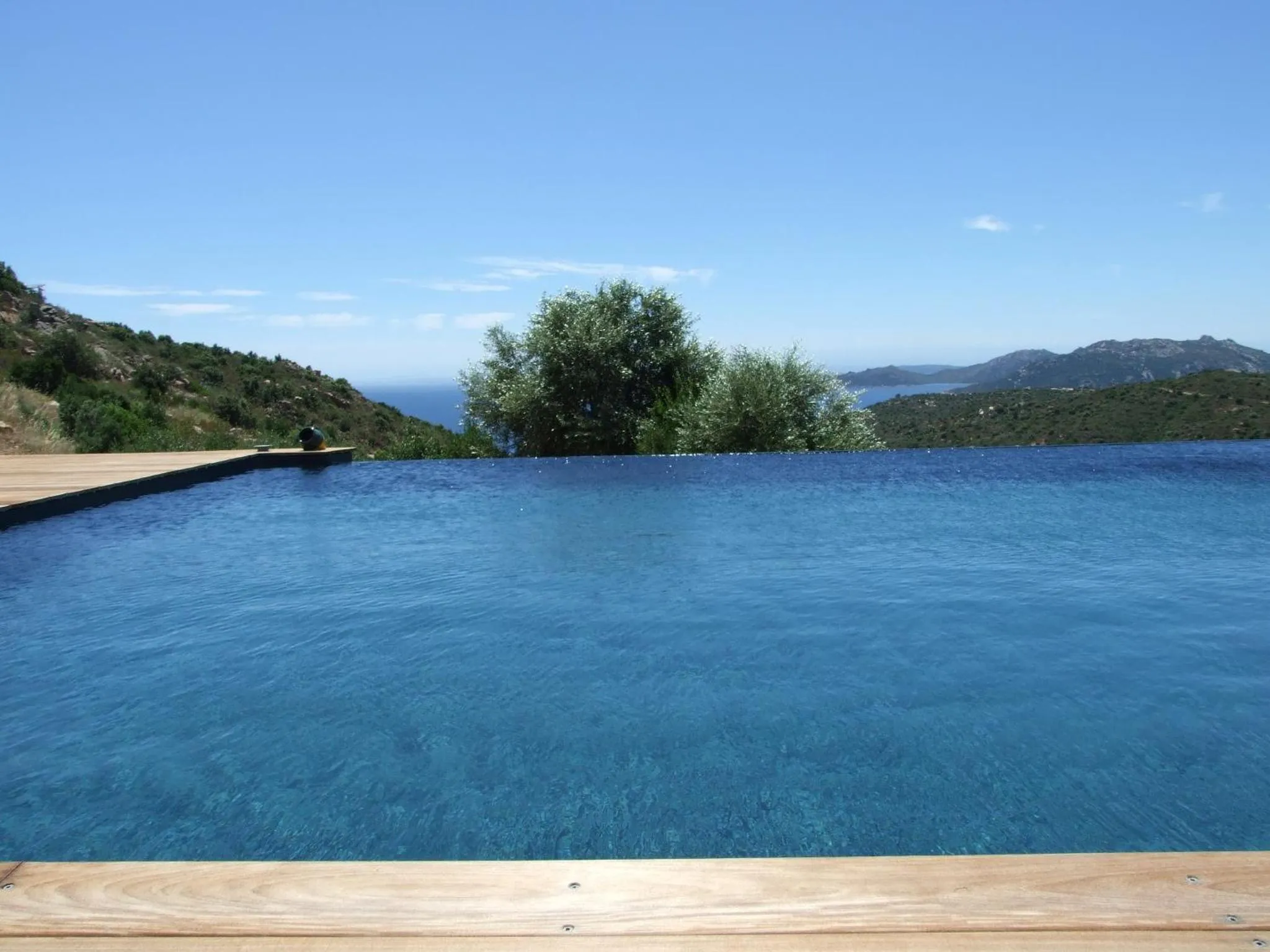 Une piscine à débordement offre une vue sur la mer et les collines environnantes.