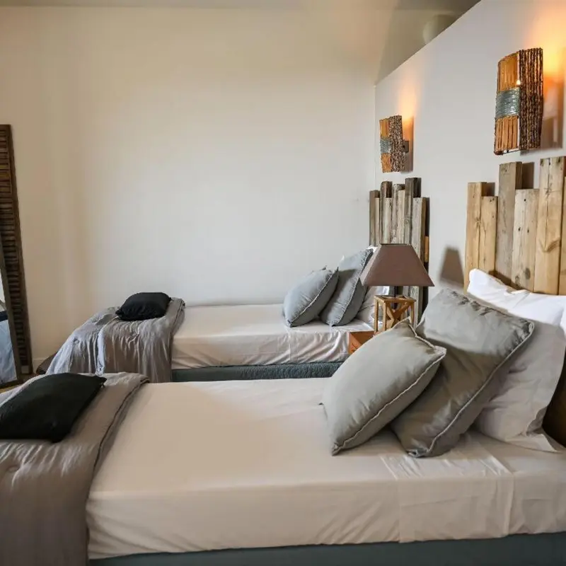 Deux lits simples avec oreillers dans une chambre lumineuse.