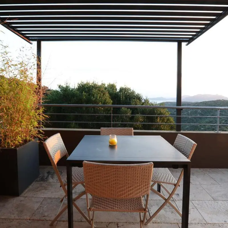 Une table et des chaises sont disposées sur une terrasse avec vue sur un paysage vallonné.
