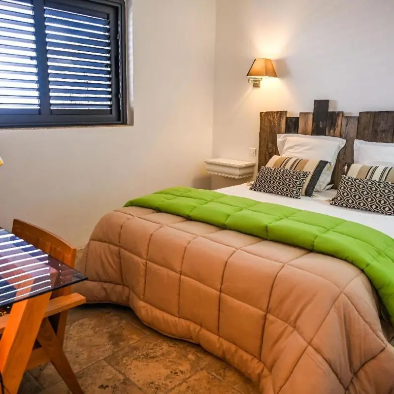 Une chambre lumineuse avec un lit recouvert d'une couette et de coussins.