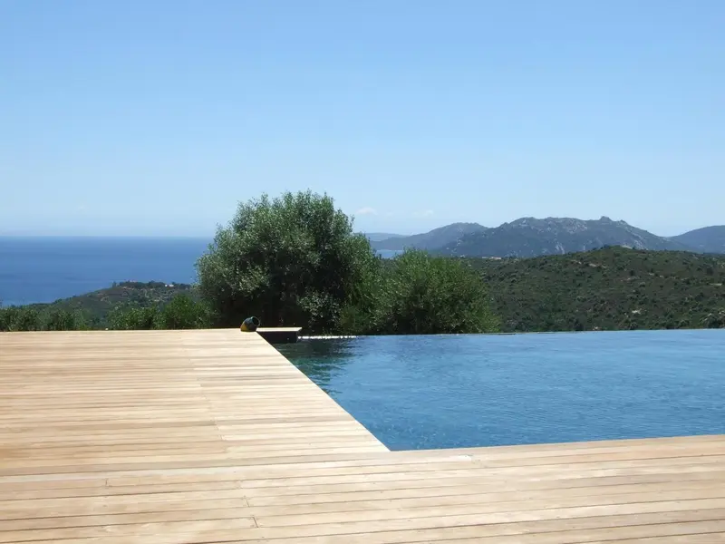 Une piscine à débordement surplombe la mer et les montagnes.