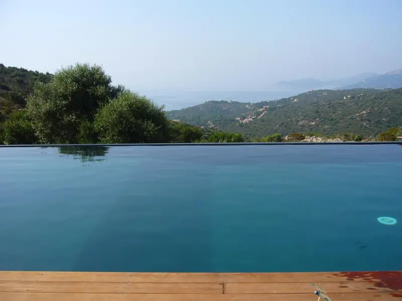 Une piscine à débordement offre une vue sur les collines verdoyantes et la mer.