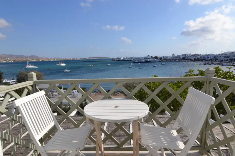 Terrasse avec mobilier blanc donnant sur une baie et des bateaux.