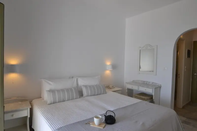 Chambre lumineuse avec un grand lit et une coiffeuse.
