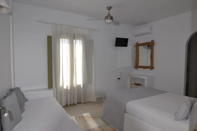 Une chambre lumineuse avec deux lits simples et un ventilateur au plafond.