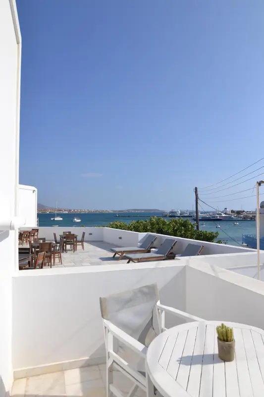 Terrasse ensoleillée avec mobilier blanc et vue sur la mer.