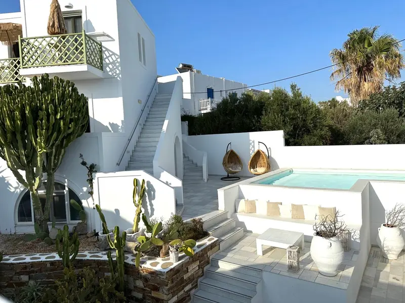 Architecture blanche et végétation luxuriante autour d'une petite piscine.