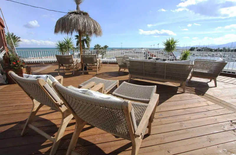 Terrasse aménagée avec des fauteuils et des parasols en bord de mer.