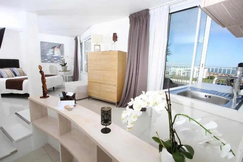 Une chambre lumineuse avec un espace cuisine et une vue sur la mer.