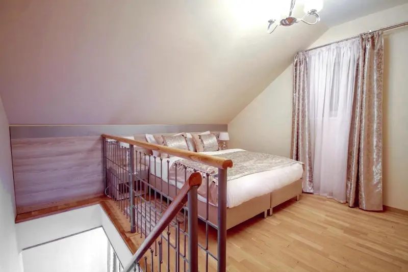Une chambre mansardée avec un lit double et des rideaux décoratifs.
