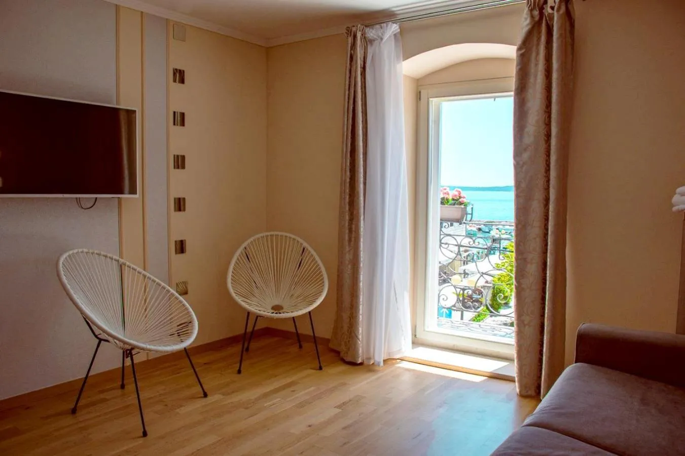 Une pièce lumineuse avec deux fauteuils en osier et une vue sur la mer.