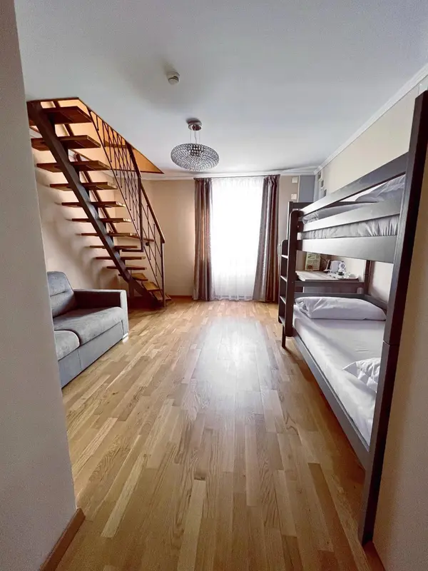 Une pièce lumineuse avec des lits superposés et un escalier en bois.
