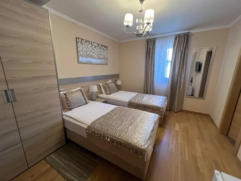 Chambre lumineuse avec deux lits simples et une décoration sobre.