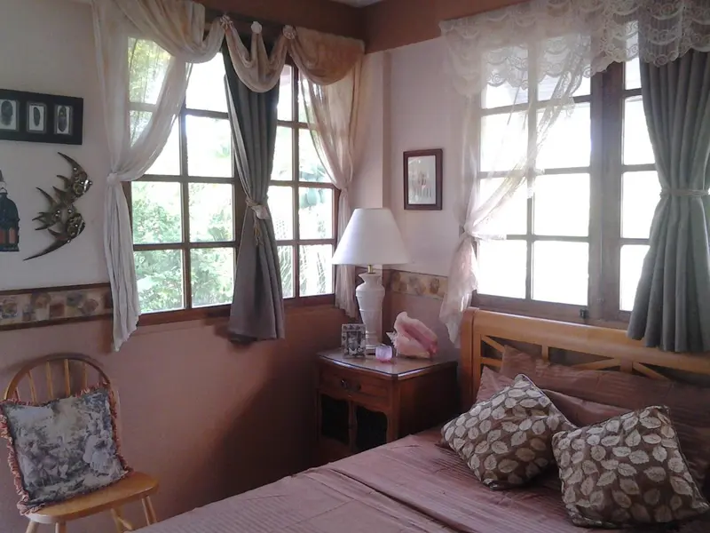 Une chambre lumineuse avec un lit et des fenêtres décorées de rideaux.