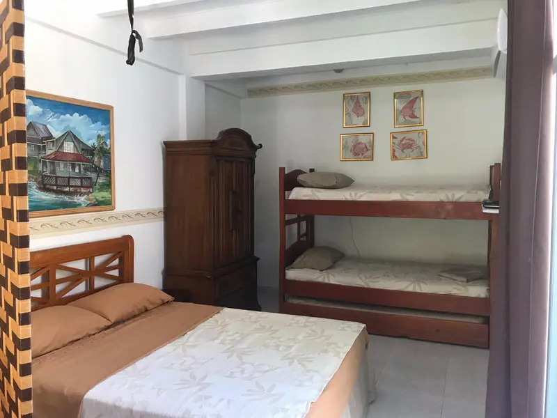 Une chambre avec un lit simple, un lit superposé et une armoire en bois.