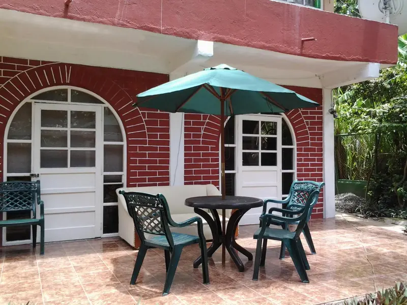 Terrasse avec mobilier de jardin devant un bâtiment rouge et blanc.