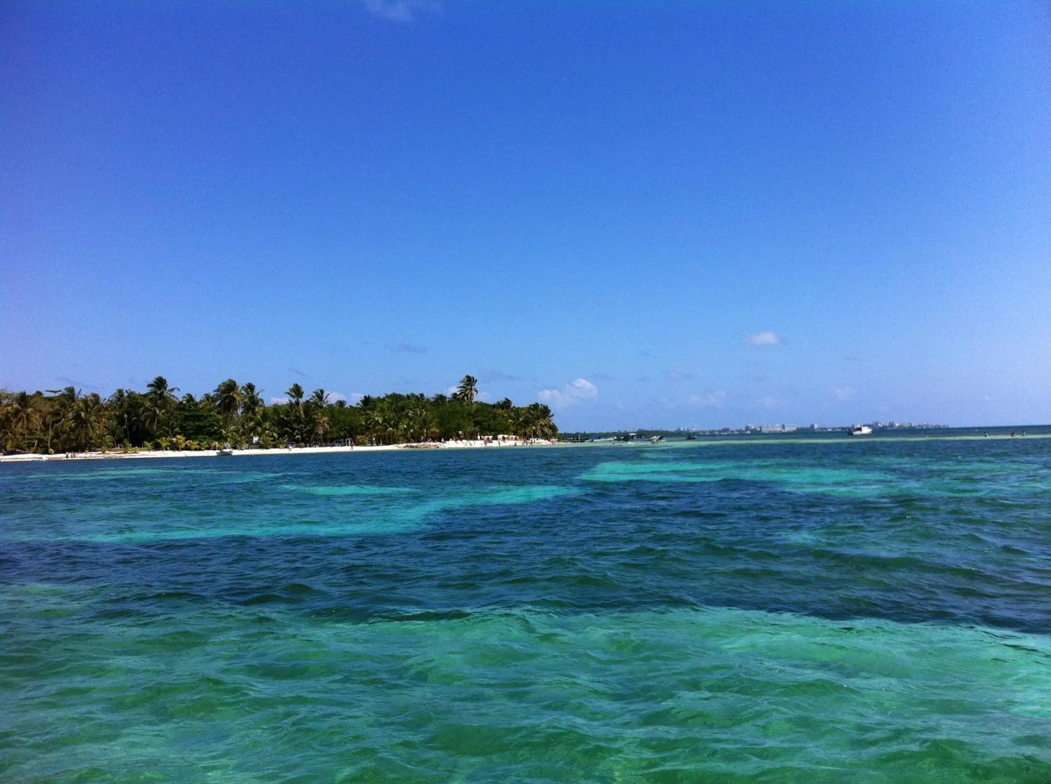 Vue sur une plage tropicale avec une eau turquoise et une végétation luxuriante.