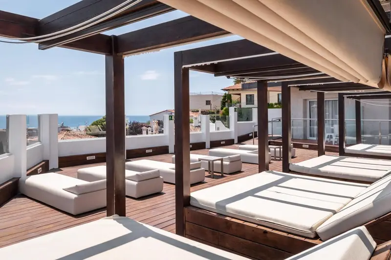 Terrasse aménagée avec des transats blancs et une vue sur la mer.