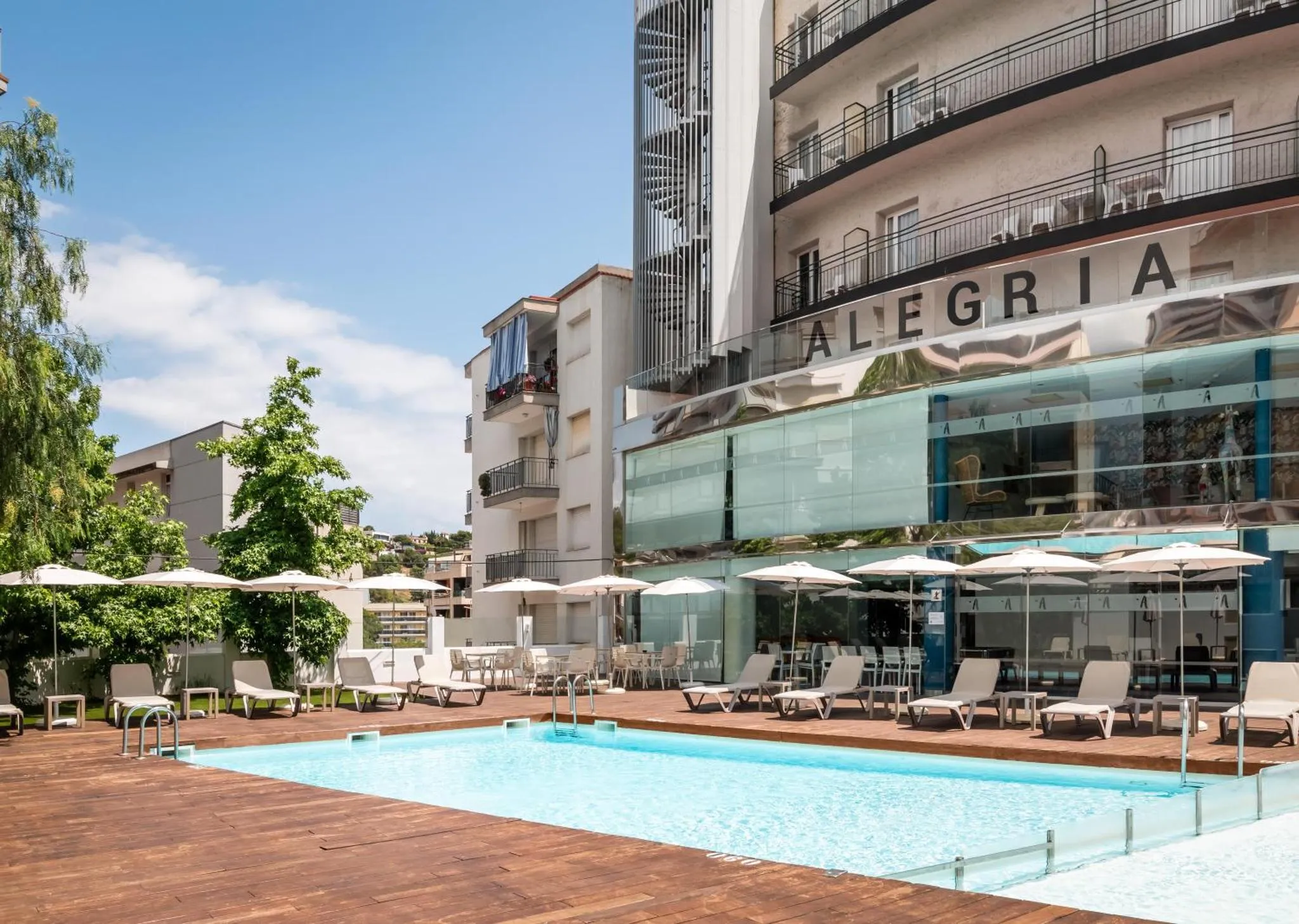 Piscine d'hôtel avec transats et parasols devant un bâtiment moderne.