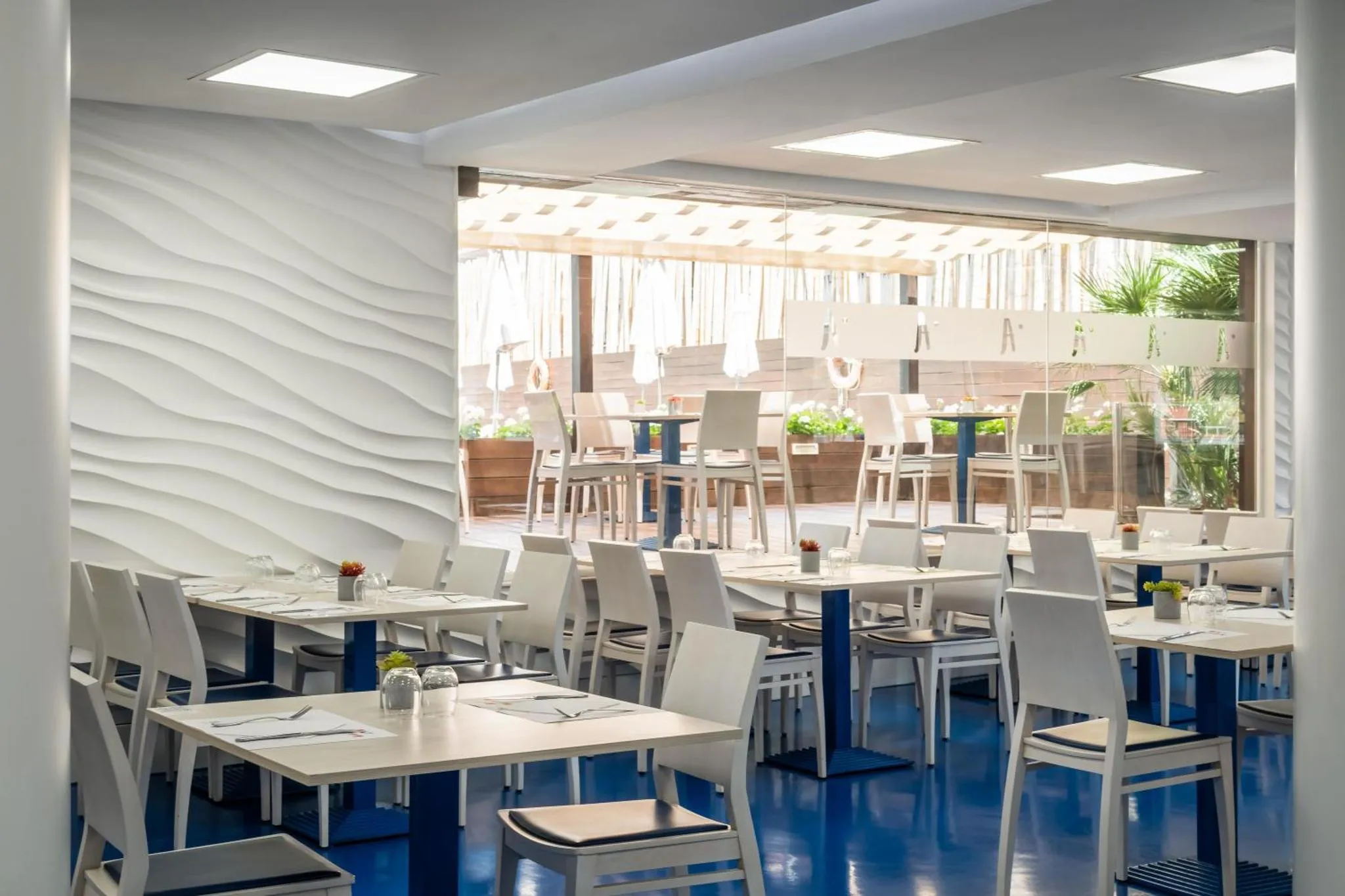 Une salle lumineuse avec des tables dressées pour un repas.