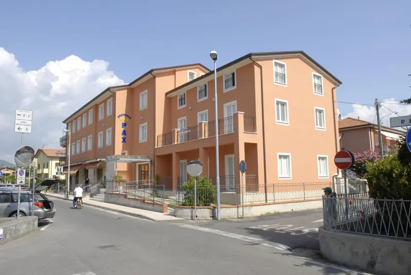 Bâtiment de couleur pêche avec des balcons et une entrée surélevée.