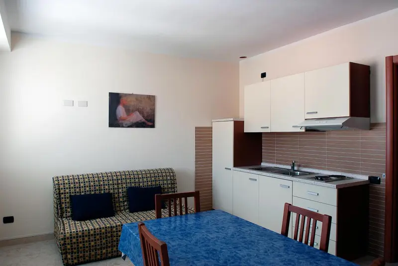 Une pièce lumineuse avec un coin repas, un canapé et une kitchenette.