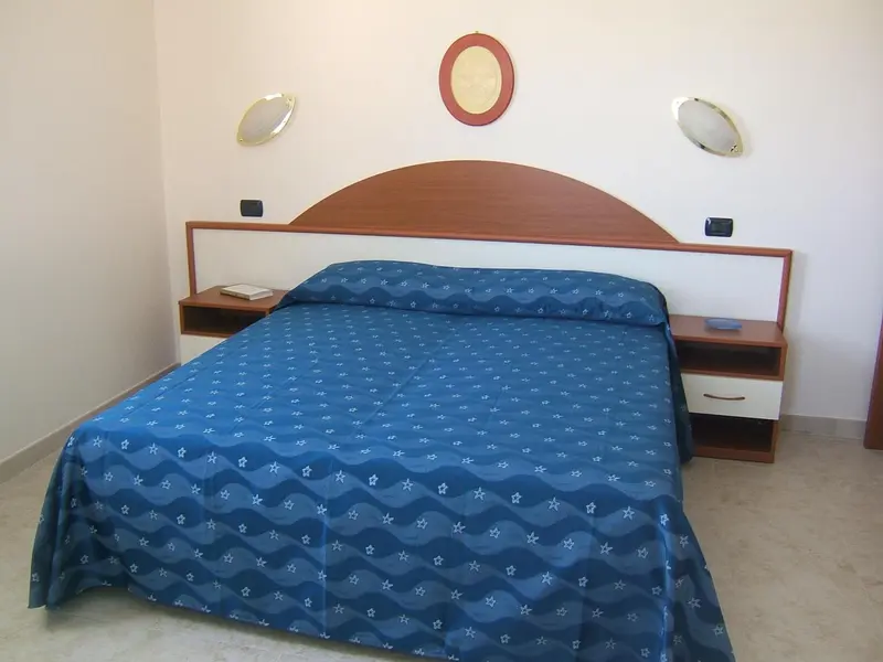 Une chambre lumineuse avec un grand lit recouvert d'une couette à motifs.