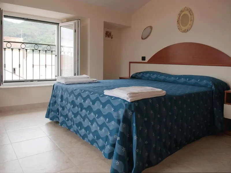 Une chambre lumineuse avec un grand lit recouvert d'une couverture bleue.