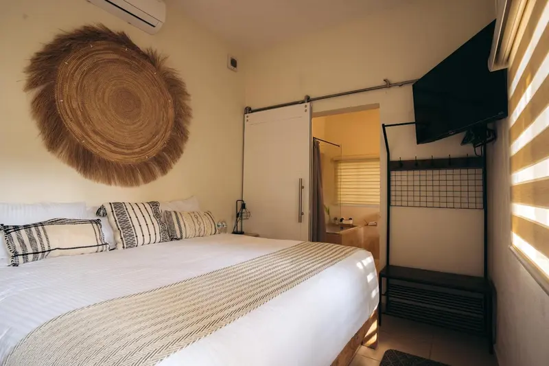 Une chambre lumineuse avec un grand lit et une décoration murale en fibres naturelles.