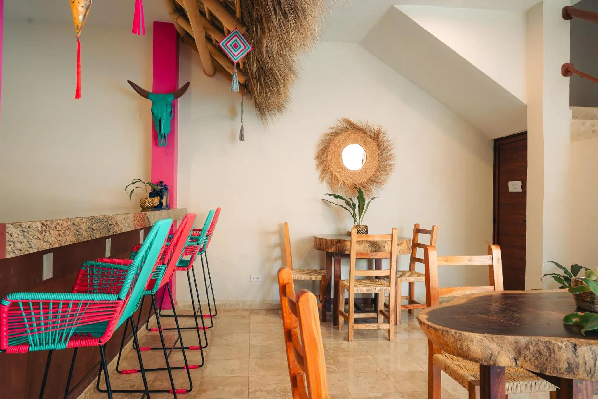 Une salle à manger lumineuse avec des chaises colorées et une table en bois.