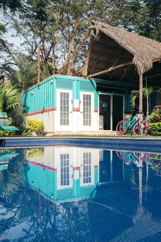 Une structure turquoise et blanche se reflète dans une piscine.