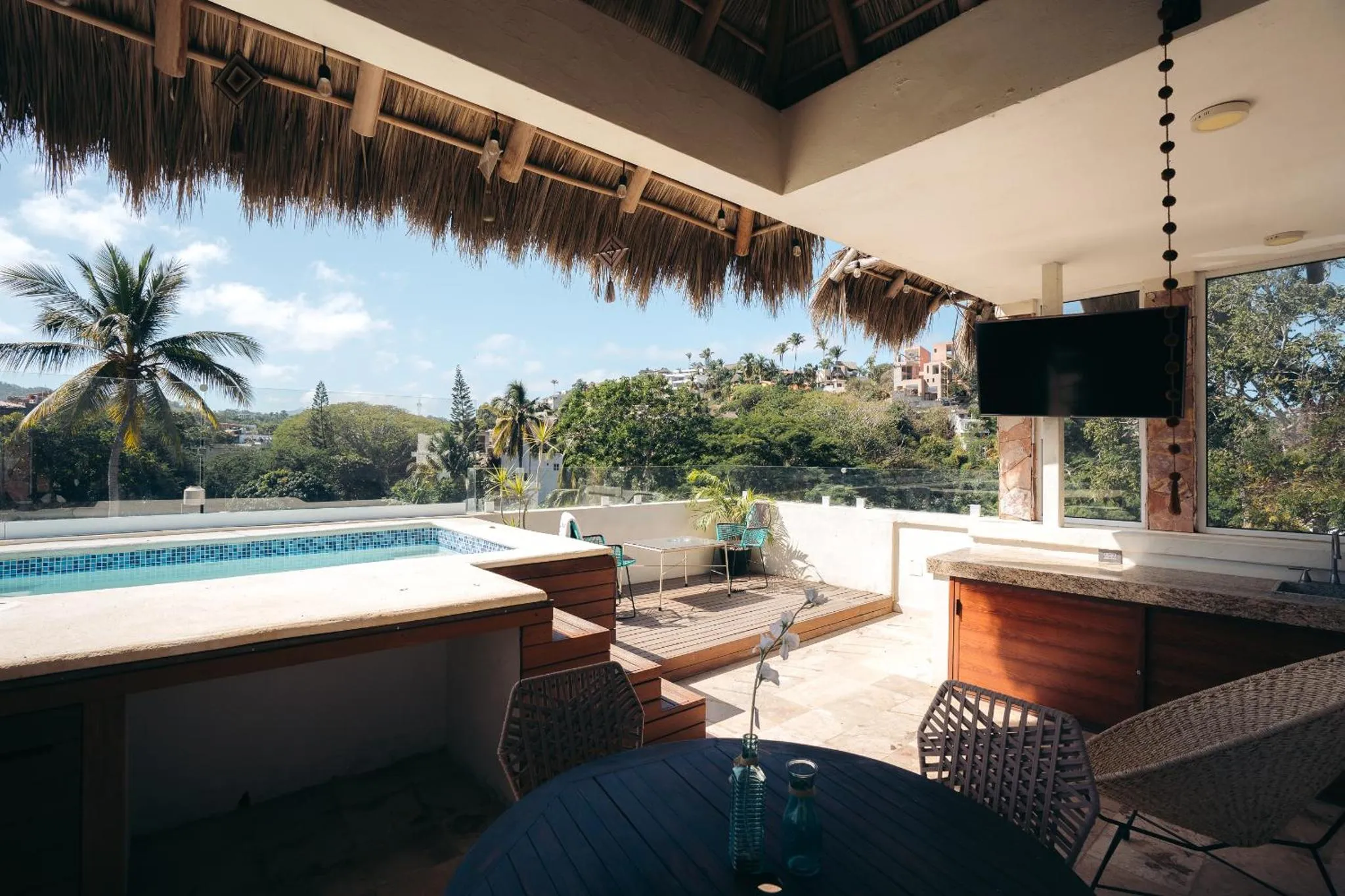 Terrasse avec piscine et mobilier de jardin offrant une vue sur la végétation et le ciel bleu.