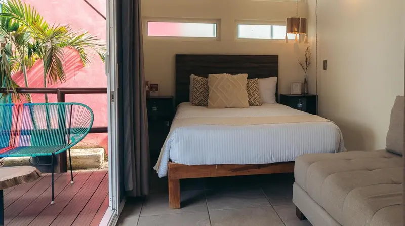Une chambre lumineuse avec un lit double et un accès à une terrasse.