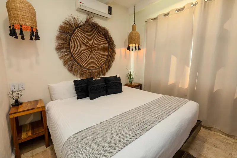 Une chambre lumineuse avec un grand lit recouvert d'une courtepointe blanche et grise.