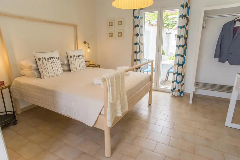 Une chambre lumineuse avec un lit double et un accès à une terrasse.