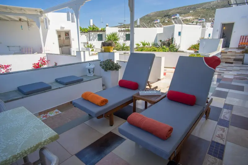Terrasse aménagée avec chaises longues et coussins colorés.
