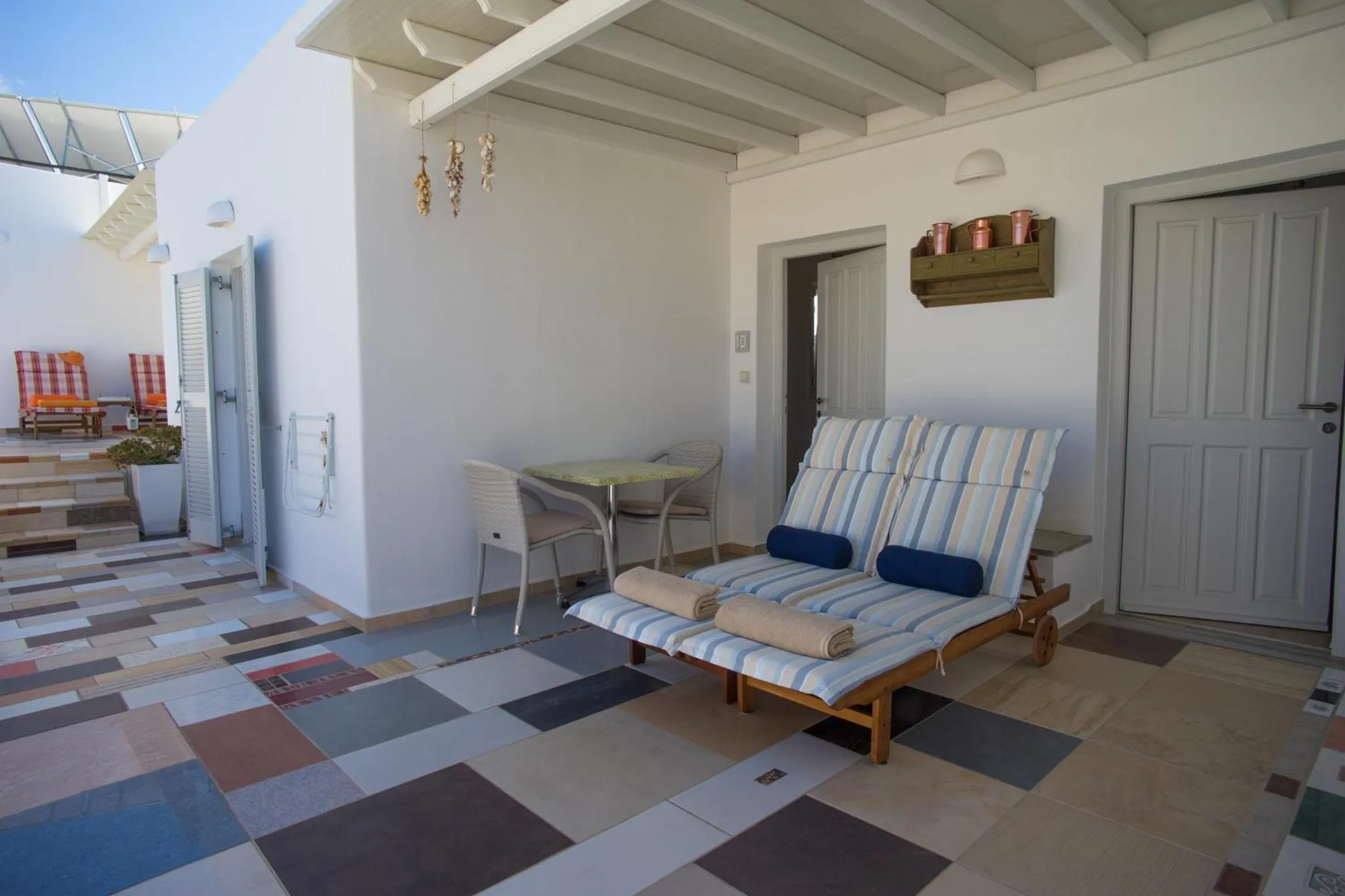 Terrasse carrelée avec mobilier de détente et petite table.
