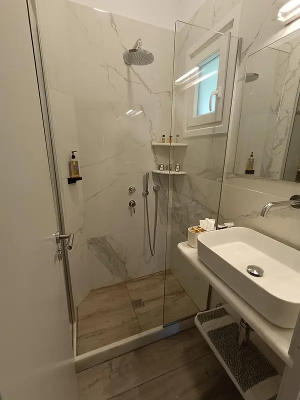 Une douche à l'italienne moderne avec carrelage clair et robinetterie chromée.