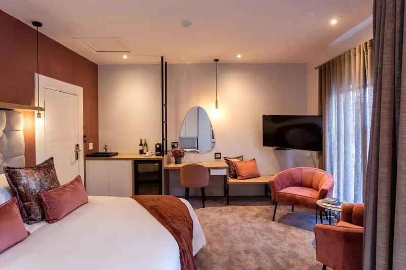 Une chambre lumineuse avec un lit, un coin salon et un bureau.