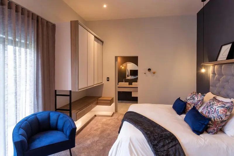 Une chambre moderne avec un grand lit et un fauteuil bleu.